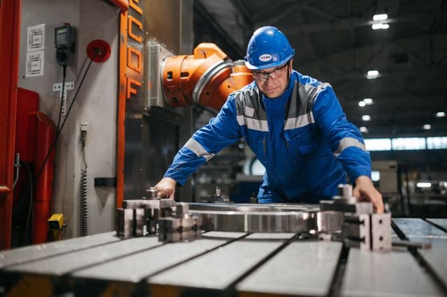 "Factory worker operating advanced industrial machinery with artificial intelligence enhancing manufacturing automation and precision production."